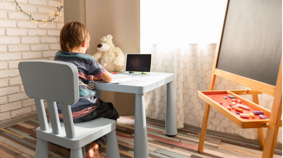 дете рисува на синя детска масичка